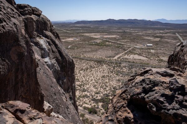 A wide shot of a section of the city of El Paso from up high behind large boulders in the foreground of the image