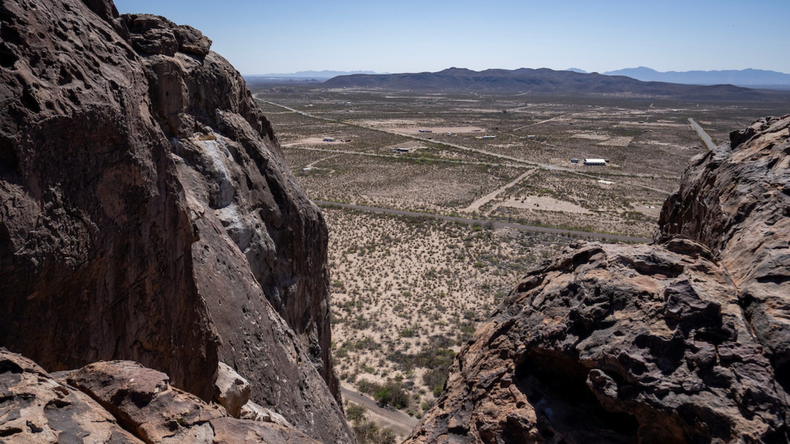 A wide shot of a section of the city of El Paso from up high behind large boulders in the foreground of the image